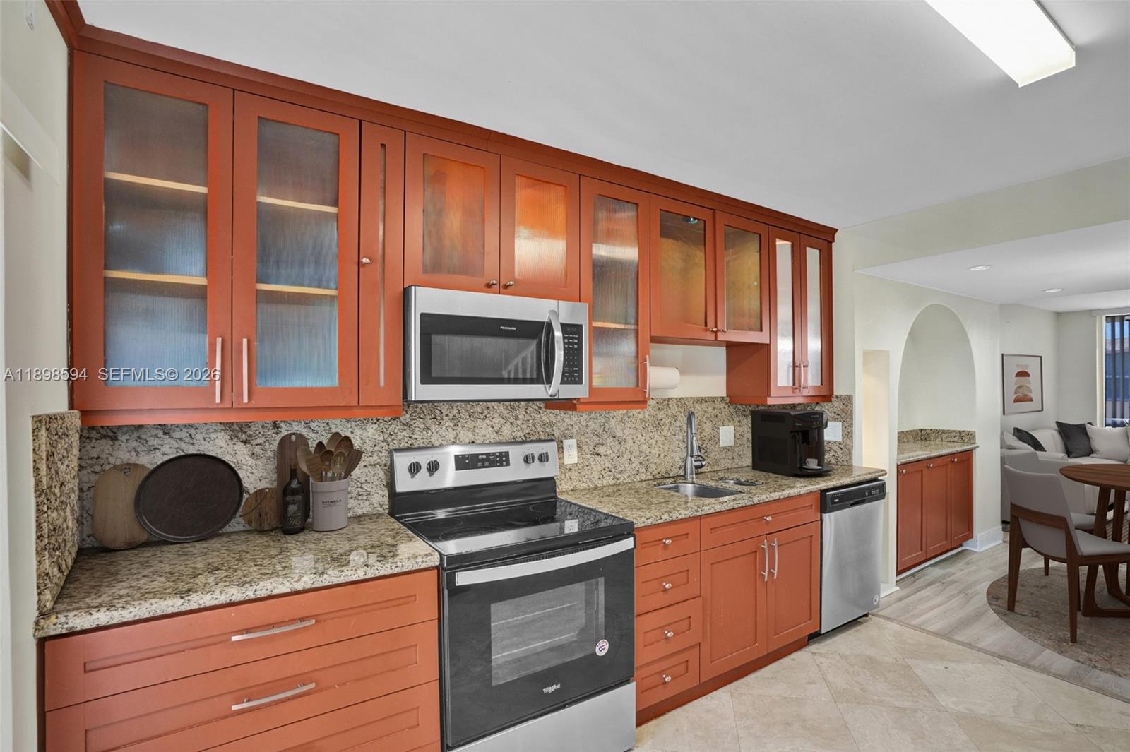 A kitchen features orange cabinets, granite countertops, stainless steel appliances, and a tiled floor — 4350 W 11th Ct # 62, Hialeah FL 33012, HIALEAH, FL