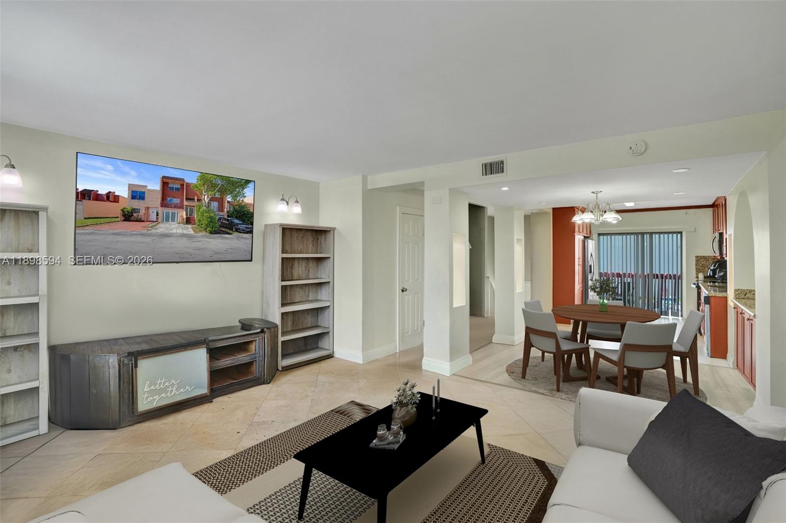 A living room with a television, bookshelves, and an adjacent dining area with tile floors — 4350 W 11th Ct # 62, Hialeah FL 33012, HIALEAH, FL