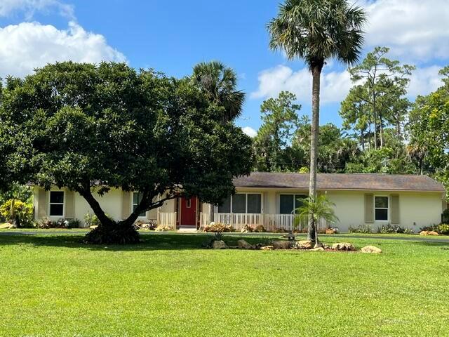 A single-story house with a large tree in the front yard under a blue sky — 6824 Lakeside Road, West Palm Beach FL 33411, WEST PALM BEACH, FL