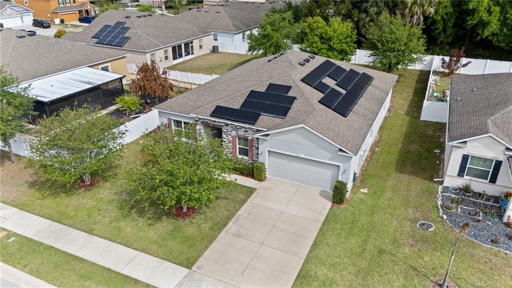 An aerial view shows a suburban house with solar panels on its shingled roof — 3609 APOPKA RIDGE CIR, APOPKA, FL