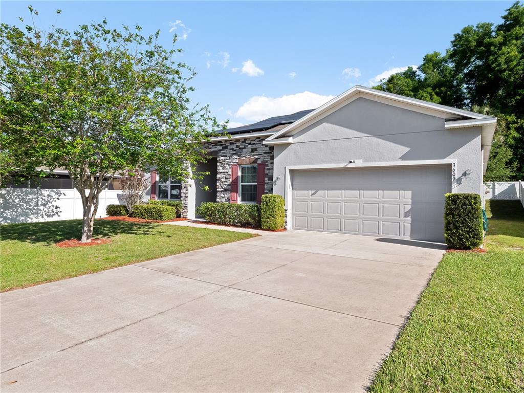A single-story house with a gray stucco exterior, stone accents, and a two-car garage — 3609 APOPKA RIDGE CIR, APOPKA, FL