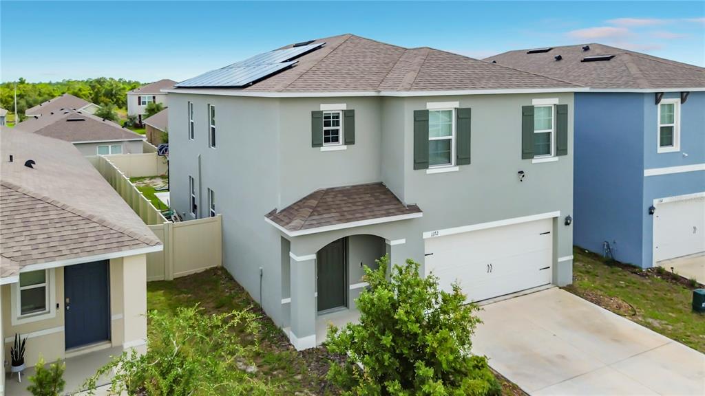An exterior view of a two-story light gray house with a solar-paneled roof — 1172 CASCADES AVENUE, DAVENPORT, FL