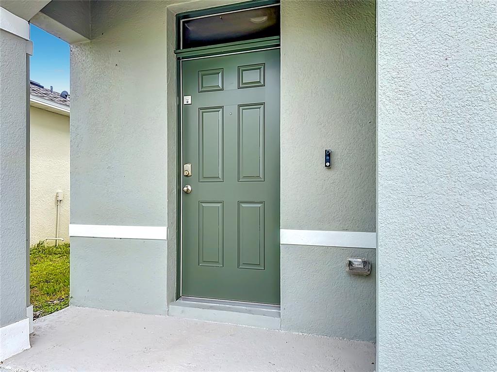 A green front door with a transom window sits on a concrete porch — 1172 CASCADES AVENUE, DAVENPORT, FL