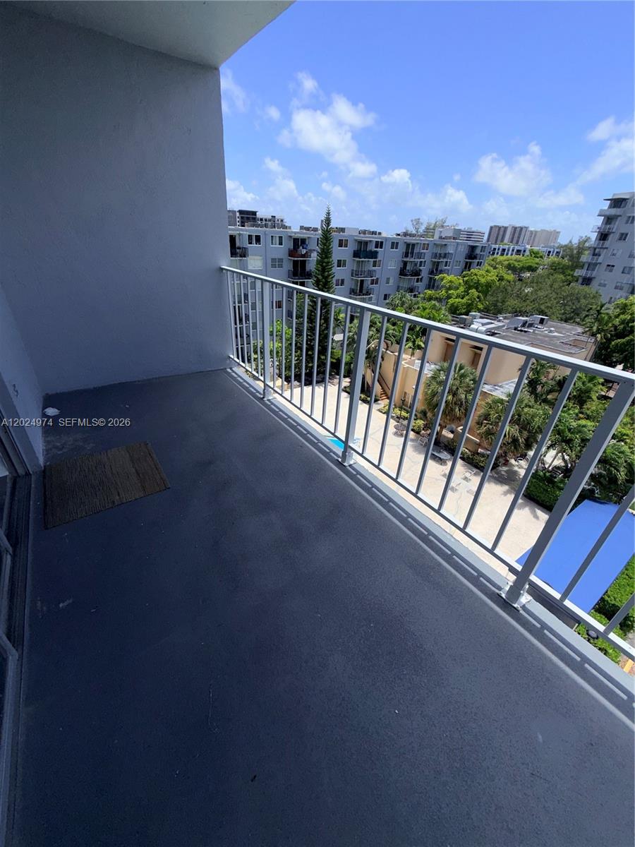 A balcony with a metal railing overlooks a courtyard and nearby apartment buildings — 1470 NE 125th Ter # 605, North Miami FL 33161, NORTH MIAMI, FL