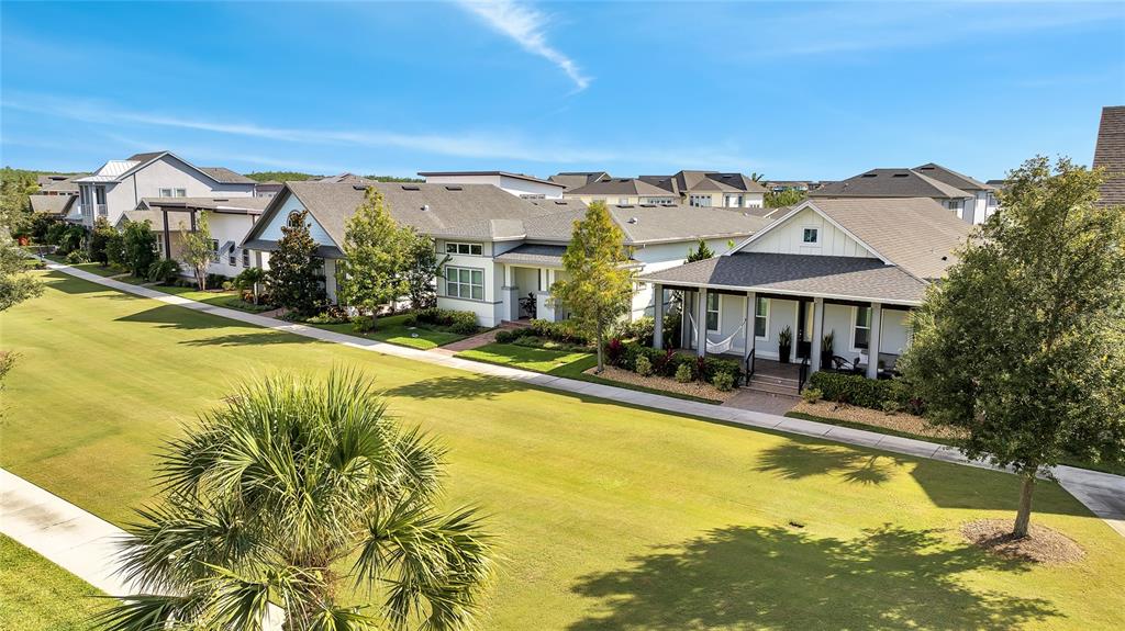 A row of suburban houses with front porches faces a large, grassy common area — 13321 BEEBE ALLEY, ORLANDO, FL