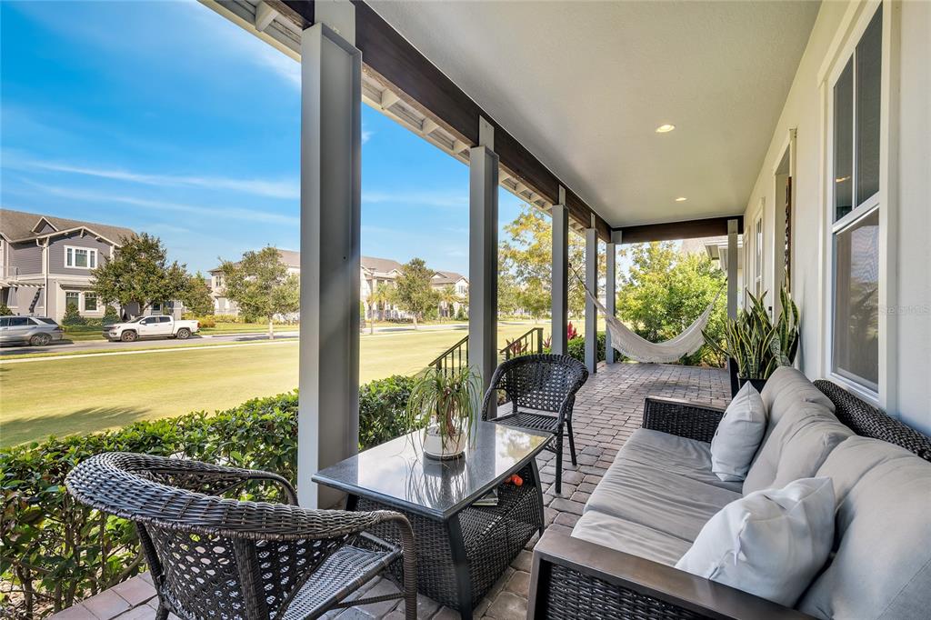 A covered porch features wicker furniture, a sofa, a hammock, and views of a neighborhood — 13321 BEEBE ALLEY, ORLANDO, FL