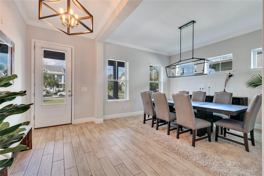 A dining room features a long table, upholstered chairs, a rectangular chandelier, and wood-look flooring — 13321 BEEBE ALLEY, ORLANDO, FL