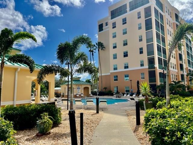 A multi-story apartment building stands behind a swimming pool and palm trees on a sunny day — 2060 MATECUMBE KEY ROAD UNIT 2301, PUNTA GORDA, FL