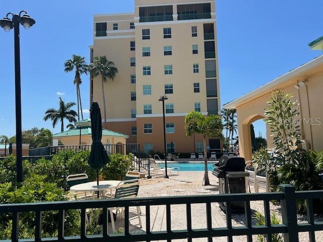 A multi-story tan building overlooks a swimming pool area with patio furniture and palm trees — 2060 MATECUMBE KEY ROAD UNIT 2301, PUNTA GORDA, FL