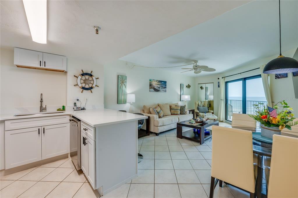 An open-concept kitchen, dining area, and living room with tile floors and ocean views — 3647 S ATLANTIC AVENUE UNIT 5B, DAYTONA BEACH, FL