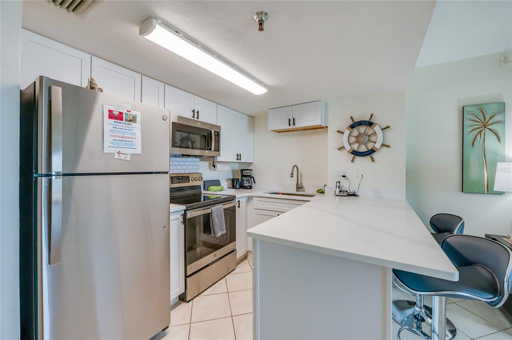 A kitchen with white cabinets, stainless steel appliances, and a white countertop breakfast bar — 3647 S ATLANTIC AVENUE UNIT 5B, DAYTONA BEACH, FL