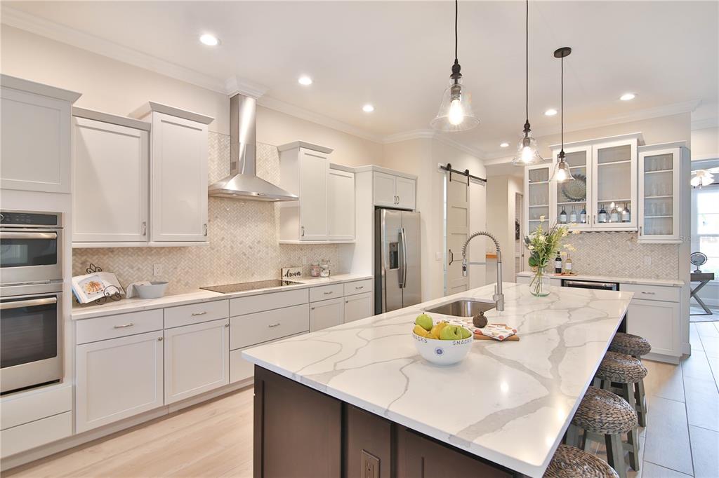 A modern kitchen features white cabinetry, a large marble island, and stainless steel appliances — 7808 34TH COURT E, SARASOTA, FL