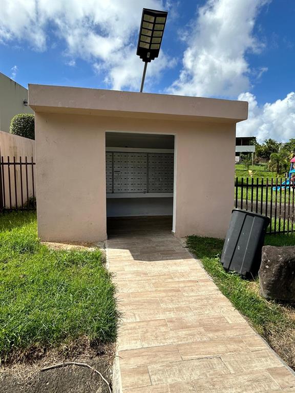 A small, beige outdoor structure houses a wall of mailboxes and features a solar light — Estancias del Verde CALLE 3 UNIT #71, RIO GRANDE, PR