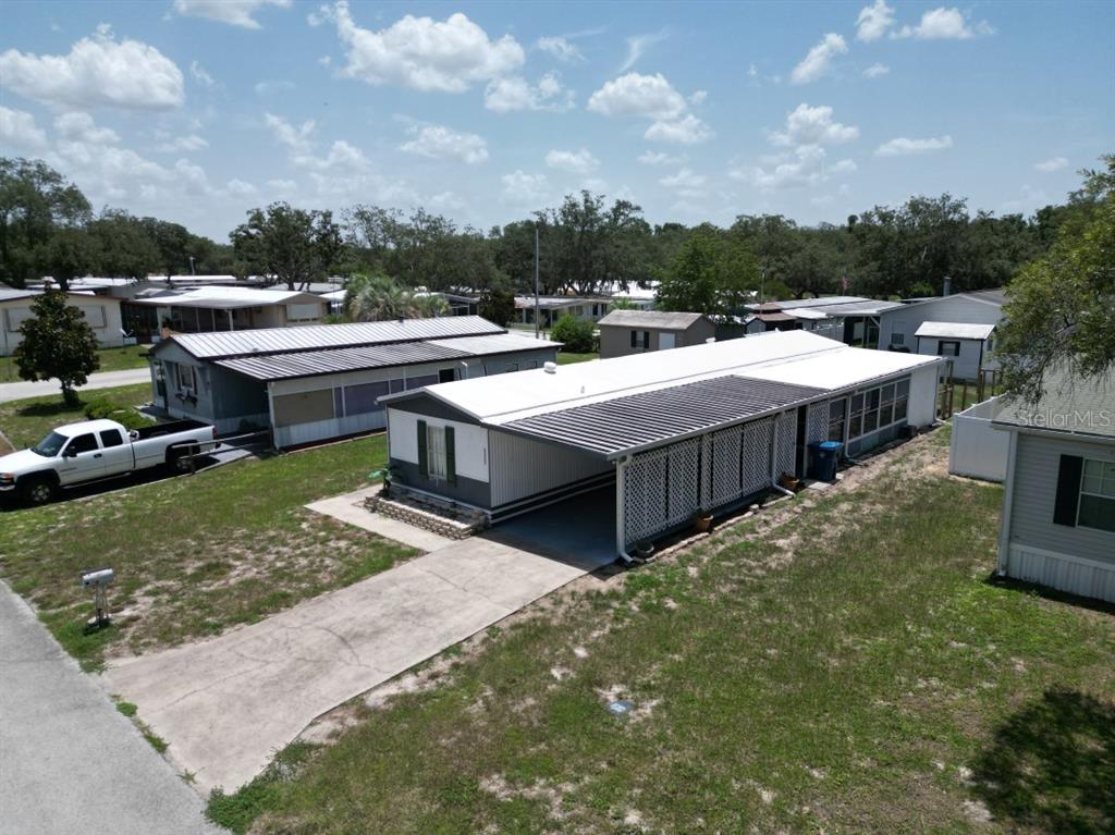 An aerial view shows a mobile home with a carport and a concrete driveway — 34940 FRASER STREET, DADE CITY, FL