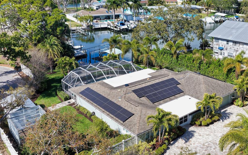 An aerial view of a house with solar panels, a pool cage, and a canal — 121 HOLLY AVENUE, SARASOTA, FL