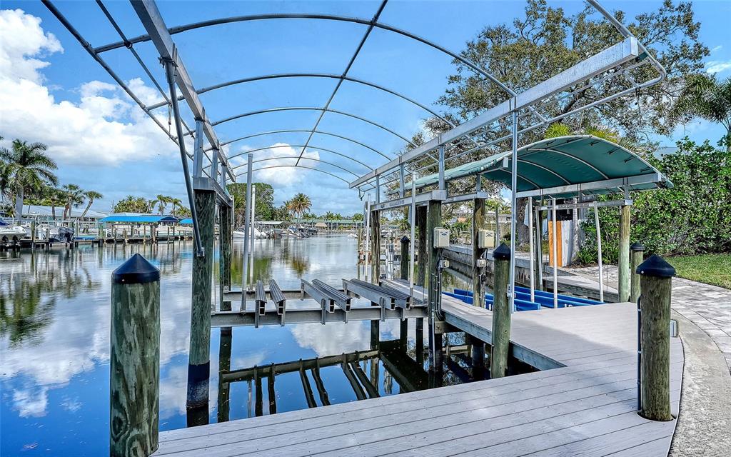 A wooden boat dock features a metal frame canopy and a boat lift over water — 121 HOLLY AVENUE, SARASOTA, FL