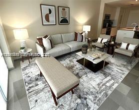 A modern living room features a beige sofa, matching bench, and patterned rug — 68 SE 6th St # 906, Miami FL 33131, MIAMI, FL