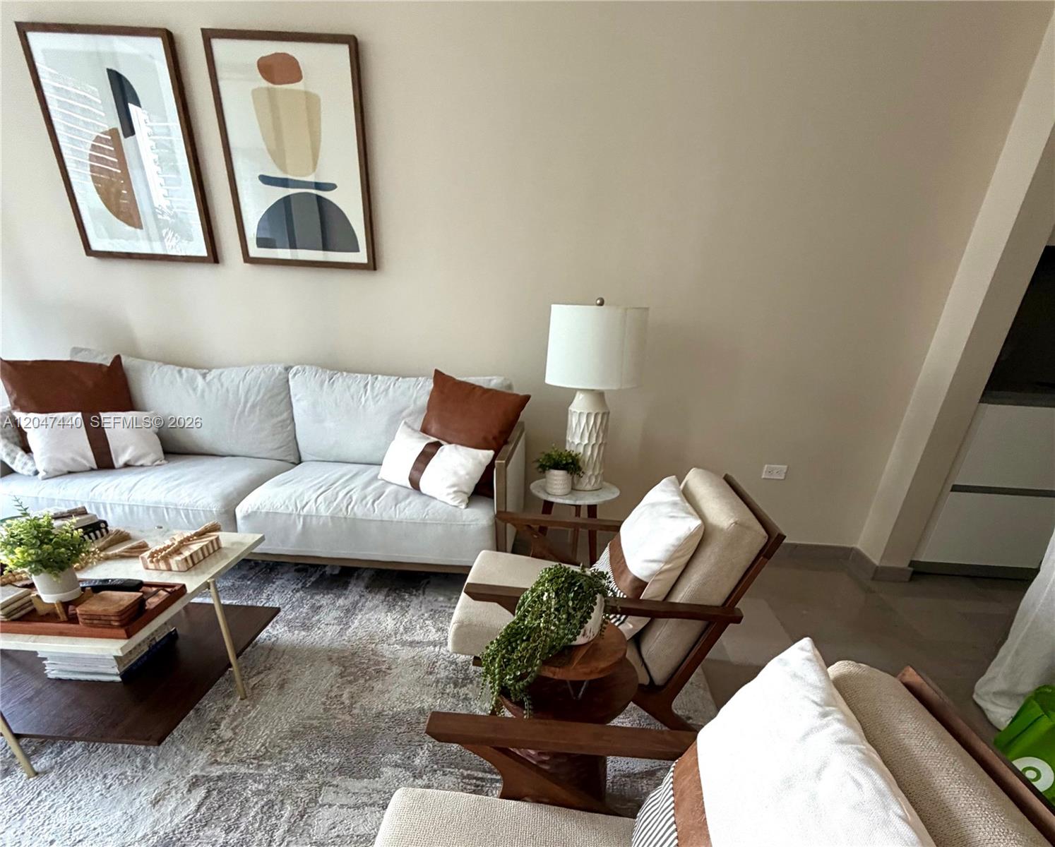 A living room features a light gray sofa, two wooden armchairs, and abstract wall art — 68 SE 6th St # 906, Miami FL 33131, MIAMI, FL