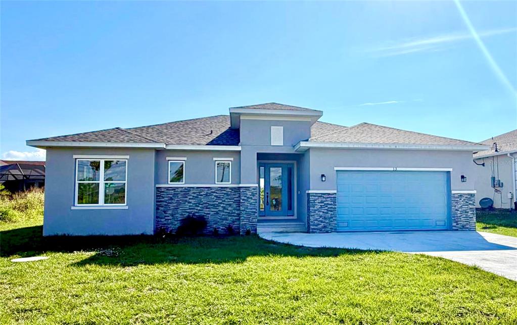 A single-story house with a gray stucco exterior, stone accents, and a two-car garage — 13 LATEEN SAIL DRIVE, PLACIDA, FL