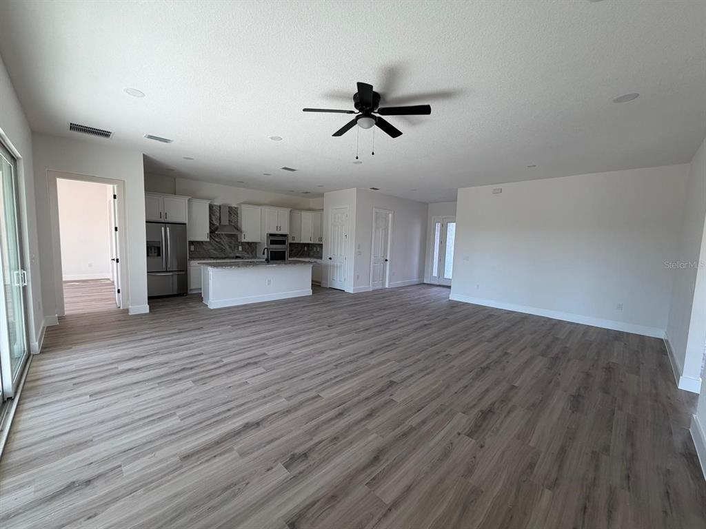 An open-concept living area features light wood-look flooring, a kitchen with white cabinets, and a ceiling fan — 13 LATEEN SAIL DRIVE, PLACIDA, FL