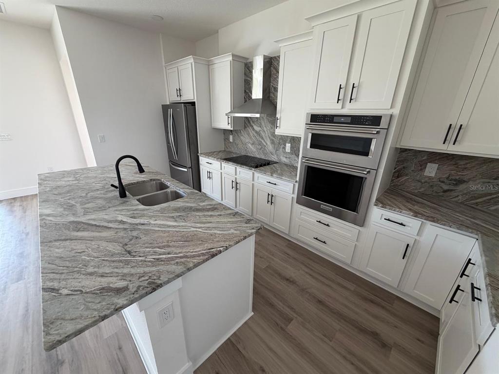 A modern kitchen features white cabinets, stone countertops, a large island, and stainless steel appliances — 13 LATEEN SAIL DRIVE, PLACIDA, FL