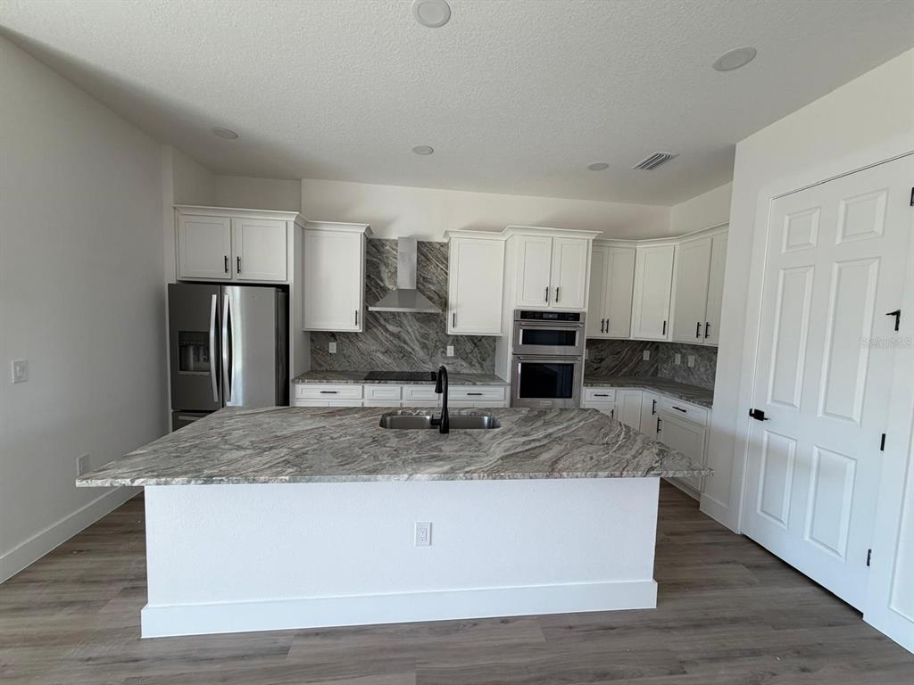 A modern kitchen features white cabinets, granite countertops, a large island, and stainless steel appliances — 13 LATEEN SAIL DRIVE, PLACIDA, FL