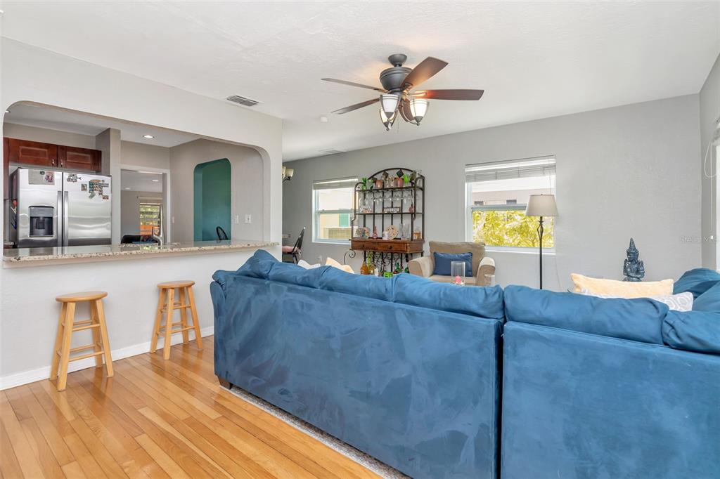 A living room with a blue sectional sofa, hardwood floors, and a kitchen pass-through window — 1223 UNION STREET, CLEARWATER, FL