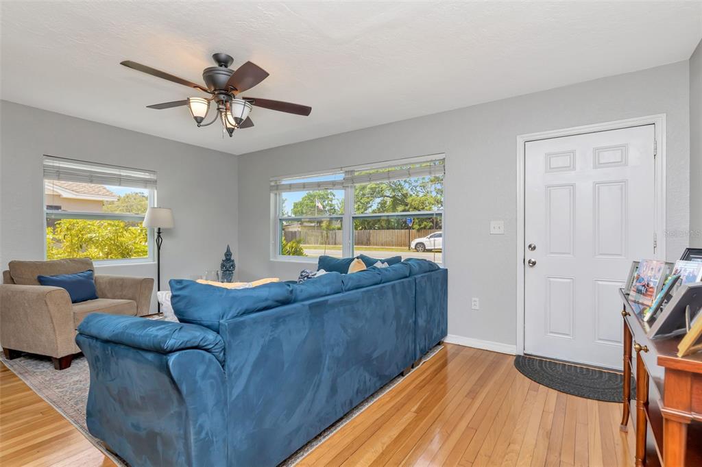 A living room features hardwood floors, a blue sectional sofa, and a white front door — 1223 UNION STREET, CLEARWATER, FL