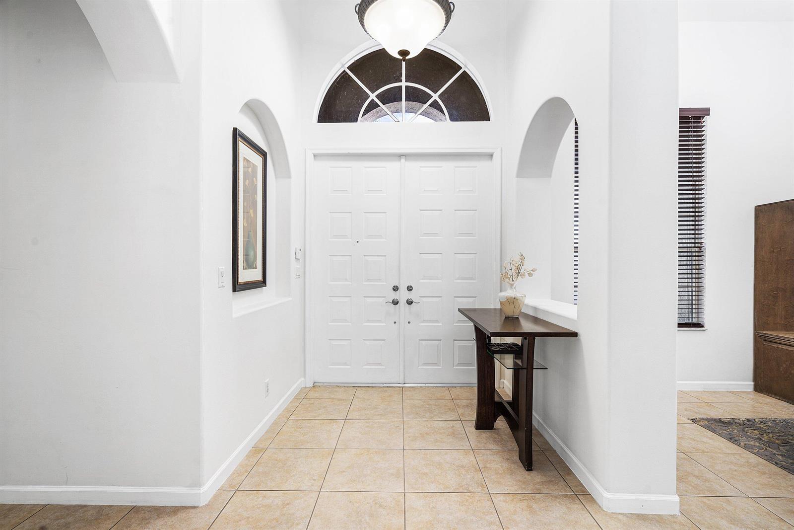 A bright entryway features white walls, tile flooring, a double door, and an arched window — 4972 Forest Dale Drive, Lake Worth FL 33449, LAKE WORTH, FL