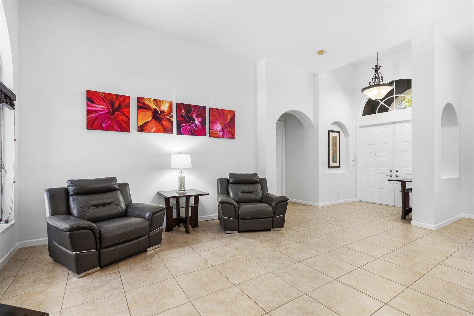 A living room with tile floors, two leather armchairs, and four floral wall canvases — 4972 Forest Dale Drive, Lake Worth FL 33449, LAKE WORTH, FL