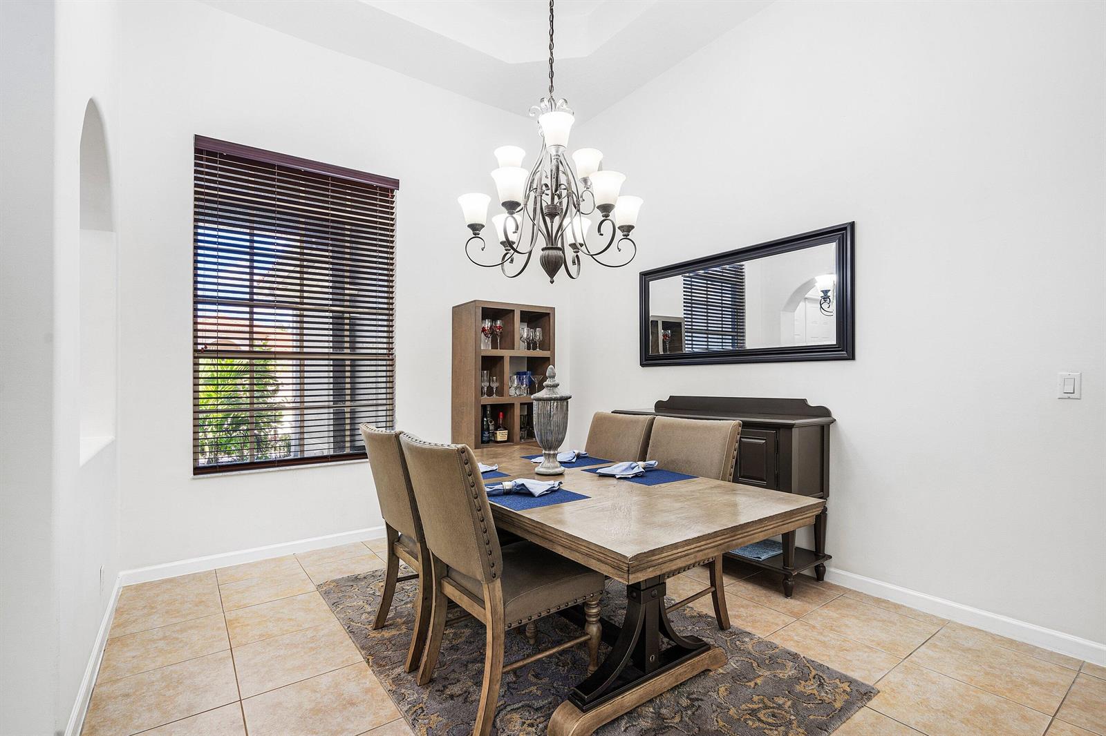 A dining room features a wooden table, upholstered chairs, a chandelier, and a large mirror — 4972 Forest Dale Drive, Lake Worth FL 33449, LAKE WORTH, FL