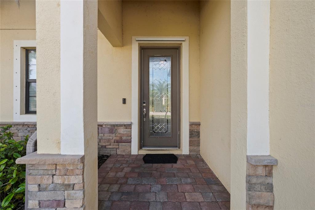 A front entryway features a paved porch, stone accents, and a glass-paneled door — 12600 RICHEZZA DRIVE, VENICE, FL