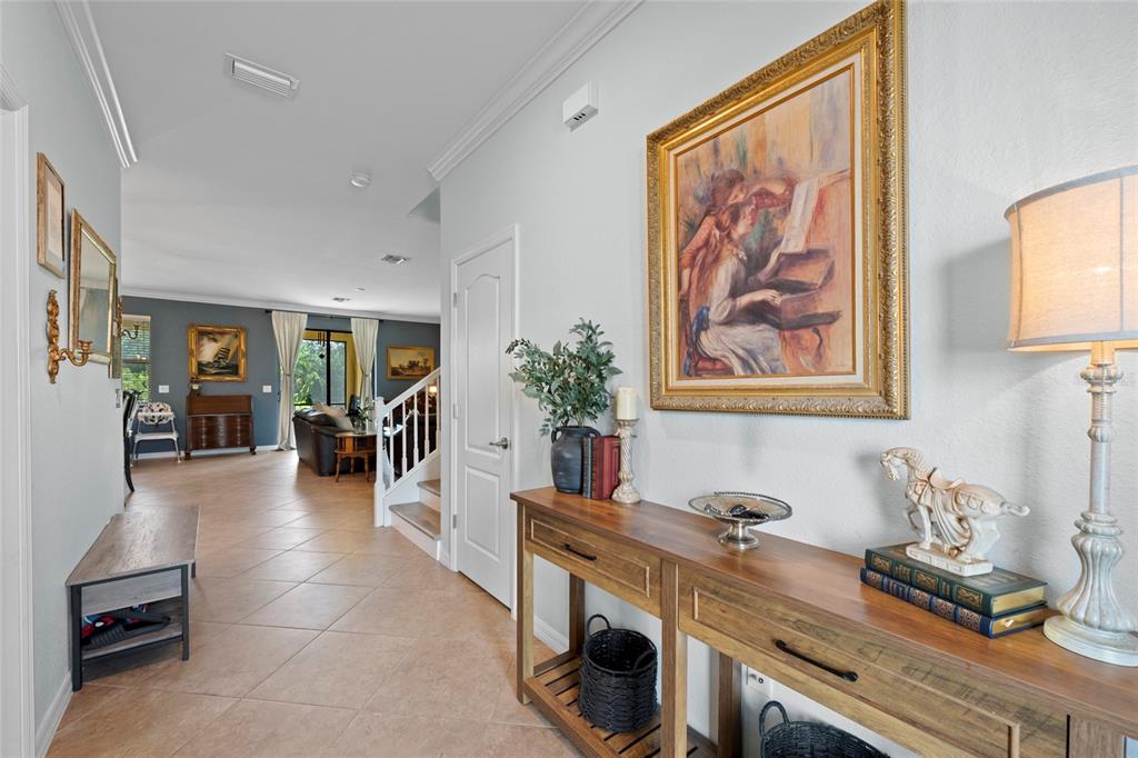 A tiled hallway features a wooden console table, wall art, and a view into a living area — 12600 RICHEZZA DRIVE, VENICE, FL
