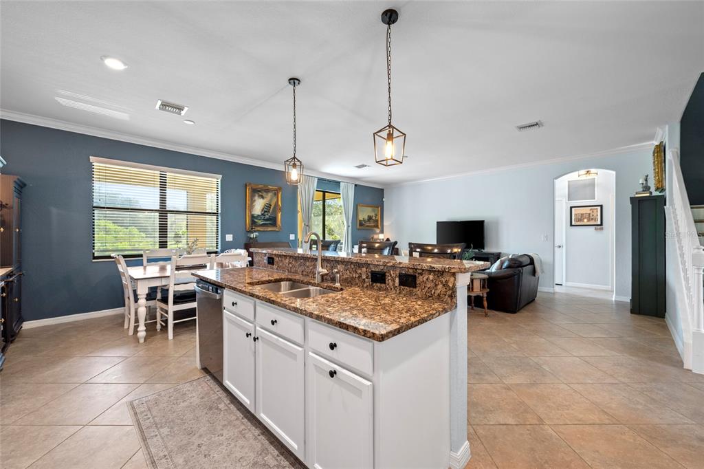 A kitchen island with granite countertops overlooks an open-concept living and dining area — 12600 RICHEZZA DRIVE, VENICE, FL