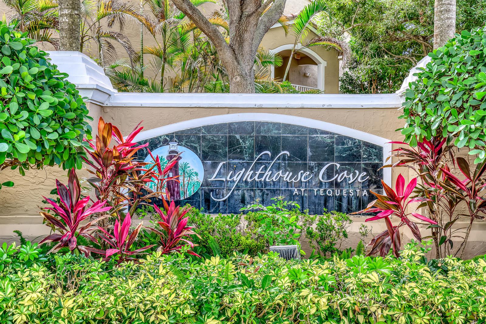 A stone sign for Lighthouse Cove at Tequesta sits surrounded by lush tropical landscaping — 278 Village Boulevard # 8208, Tequesta FL 33469, TEQUESTA, FL