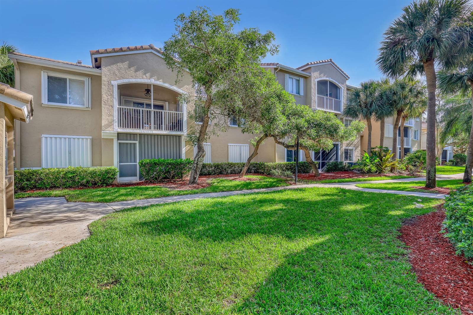 A multi-story apartment building with tan stucco walls, screened balconies, and surrounding landscaped grounds — 278 Village Boulevard # 8208, Tequesta FL 33469, TEQUESTA, FL