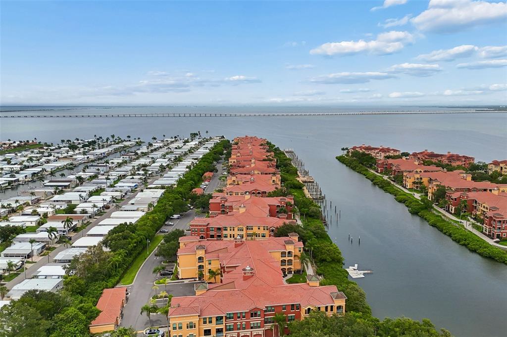 An aerial view shows a multi-story residential complex situated between a canal and mobile homes — 2717 VIA CIPRIANI UNIT 623A, CLEARWATER, FL