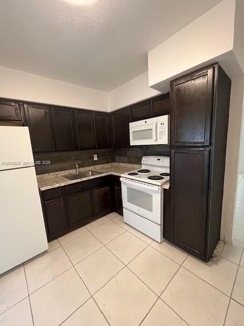 A kitchen features dark wood cabinets, white appliances, and light-colored tile flooring — 901 SW 4th Ter, Hallandale Beach FL 33009, HALLANDALE BEACH, FL