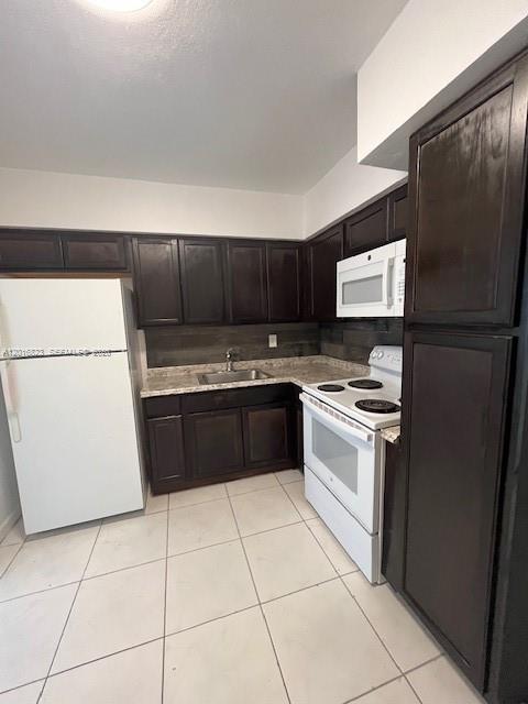 A kitchen features dark wood cabinets, white appliances, and light-colored tile flooring — 901 SW 4th Ter, Hallandale Beach FL 33009, HALLANDALE BEACH, FL