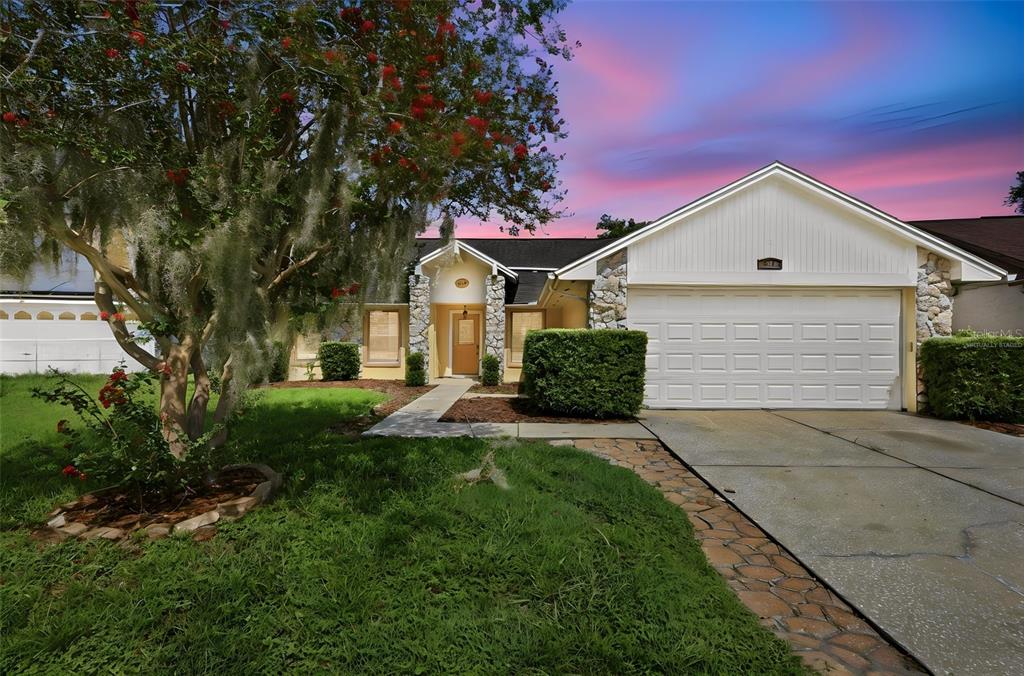 A single-story house with a white garage, stone accents, and a large tree in front — 720 TOMLINSON TERRACE, LAKE MARY, FL
