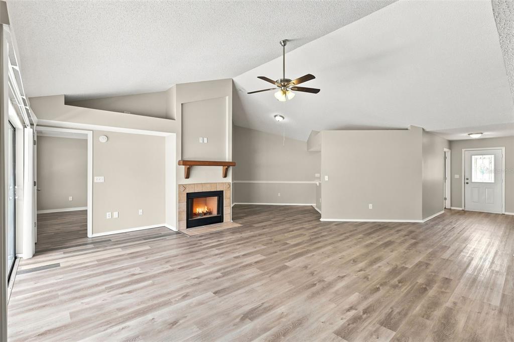 A living room with light wood-look flooring, a fireplace, a ceiling fan, and white walls — 720 TOMLINSON TERRACE, LAKE MARY, FL