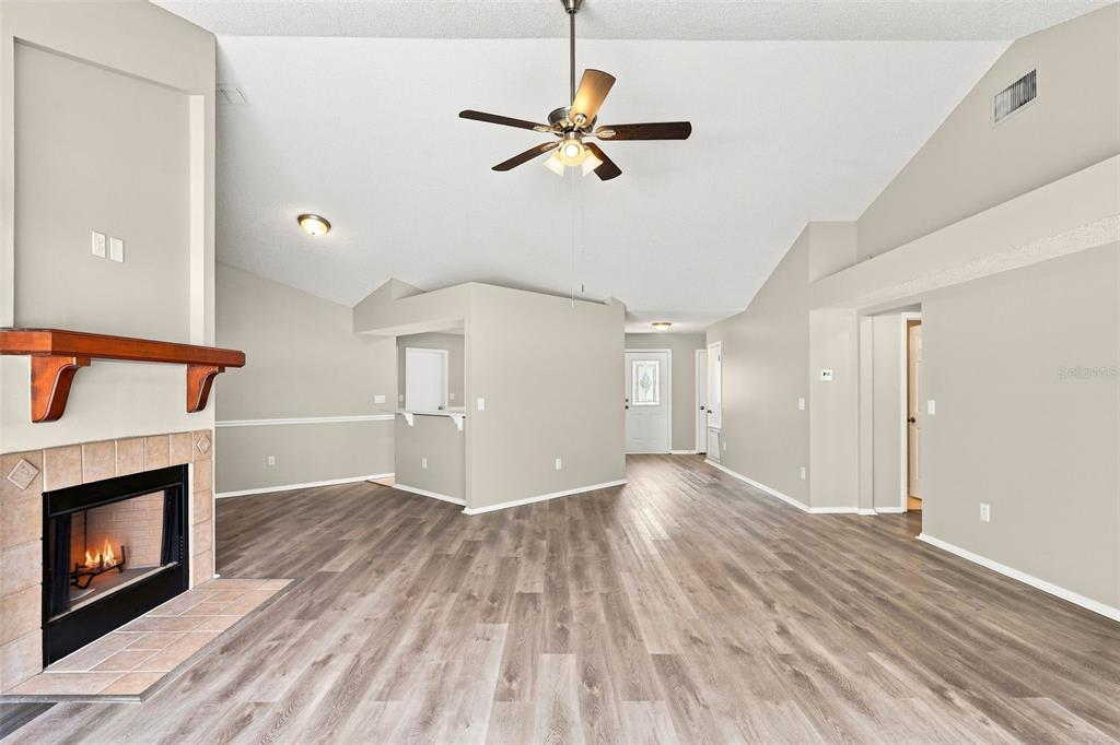 A living room with wood-look flooring, a vaulted ceiling, and a fireplace with a mantel — 720 TOMLINSON TERRACE, LAKE MARY, FL