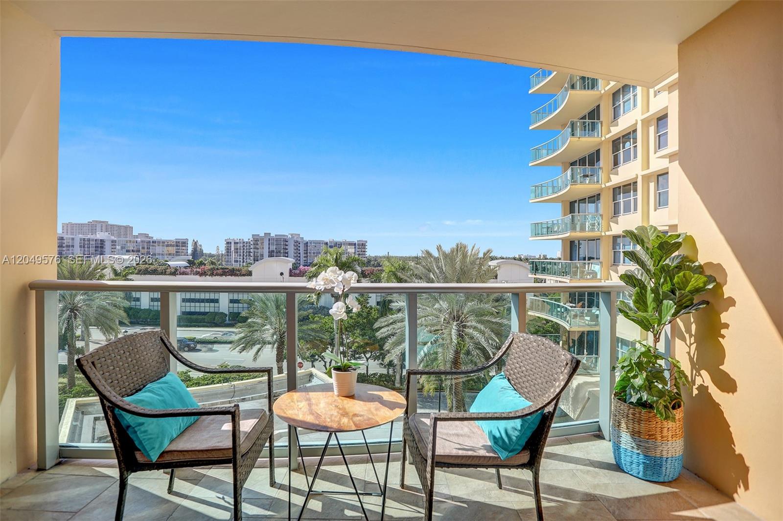 A balcony features two wicker chairs, a small round table, and a potted plant — 2501 S Ocean Dr, Hollywood FL 33019, HOLLYWOOD, FL