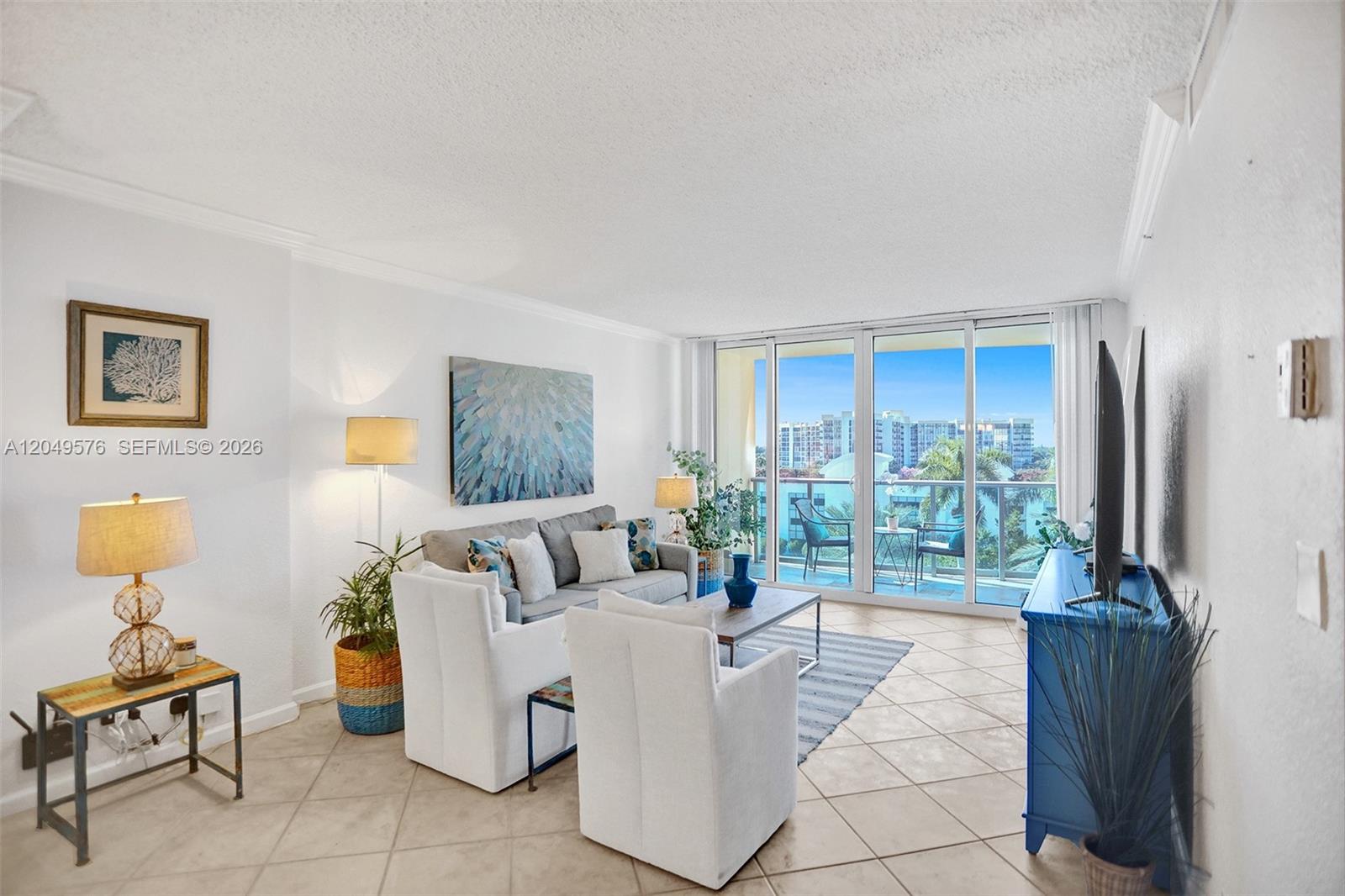 A living room features white walls, tile flooring, a gray sofa, and a balcony view — 2501 S Ocean Dr, Hollywood FL 33019, HOLLYWOOD, FL