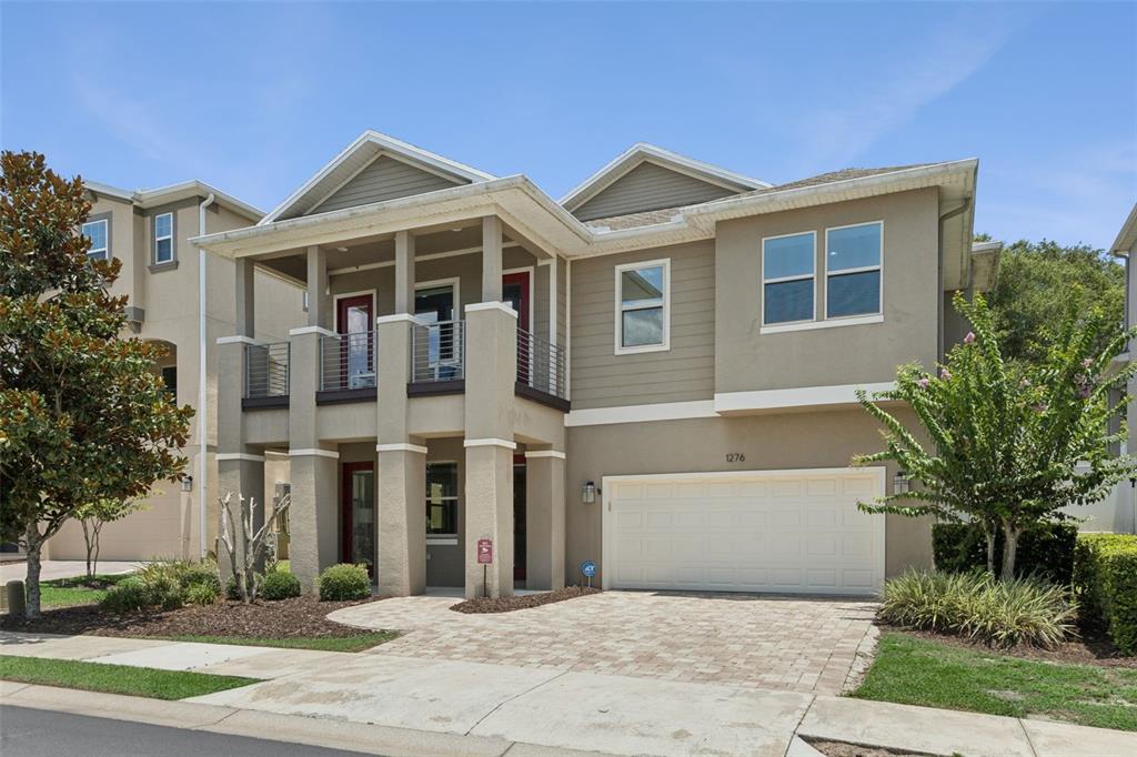 A two-story house with a beige stucco exterior, a two-car garage, and a front balcony — 1276 DORA PARC LANE, MOUNT DORA, FL