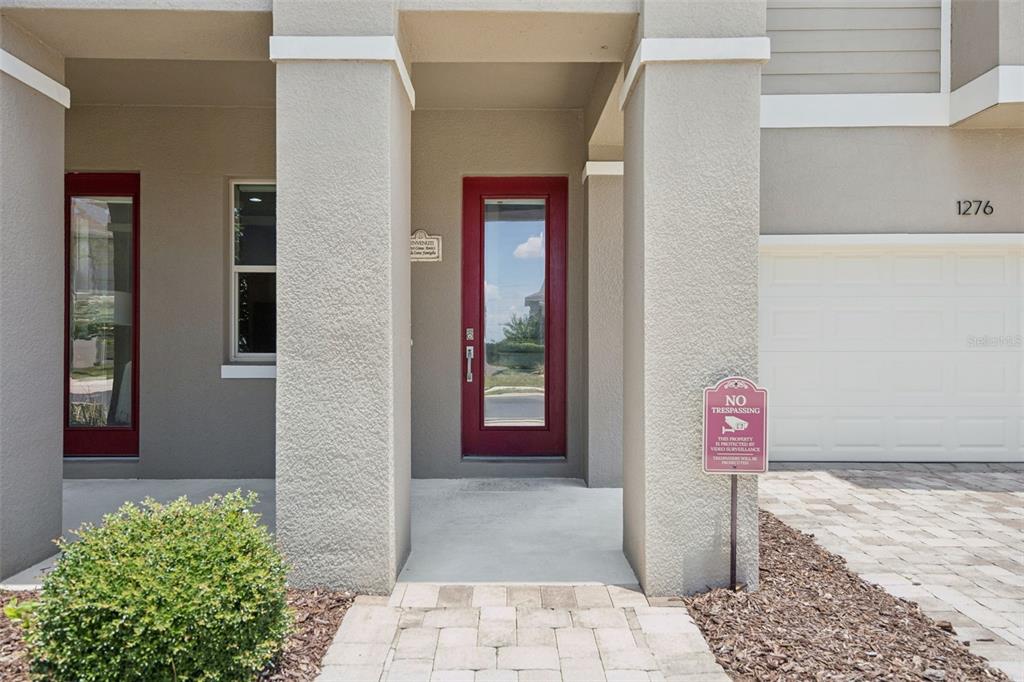 The exterior of a house features a red front door, a garage, and a walkway — 1276 DORA PARC LANE, MOUNT DORA, FL