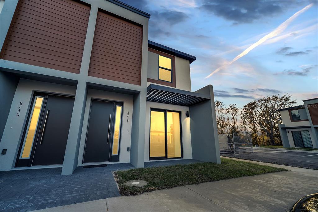 The exterior of a modern two-story townhouse features gray walls, wood-look siding, and glass doors — 8752 GOOD VIBES PLACE, KISSIMMEE, FL