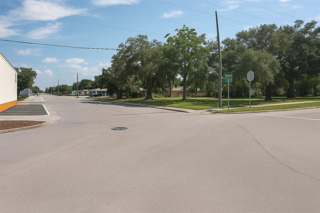 An outdoor view of a paved street intersection with trees and a building corner — 203 EMERALD AVENUE, LAKE WALES, FL