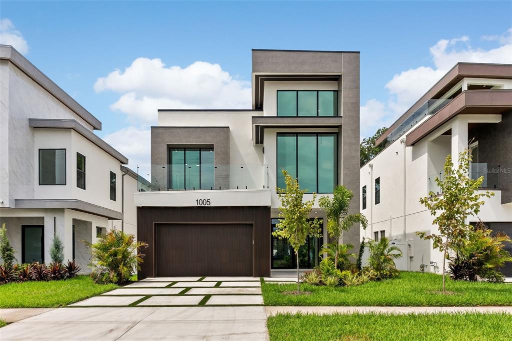 A modern two-story house with a dark wood garage, glass balcony, and large windows — 1005 W BRADDOCK STREET, TAMPA, FL