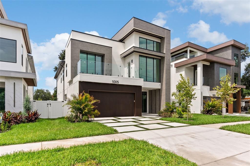 A modern two-story house with a dark wood garage door and a glass-railed balcony — 1005 W BRADDOCK STREET, TAMPA, FL